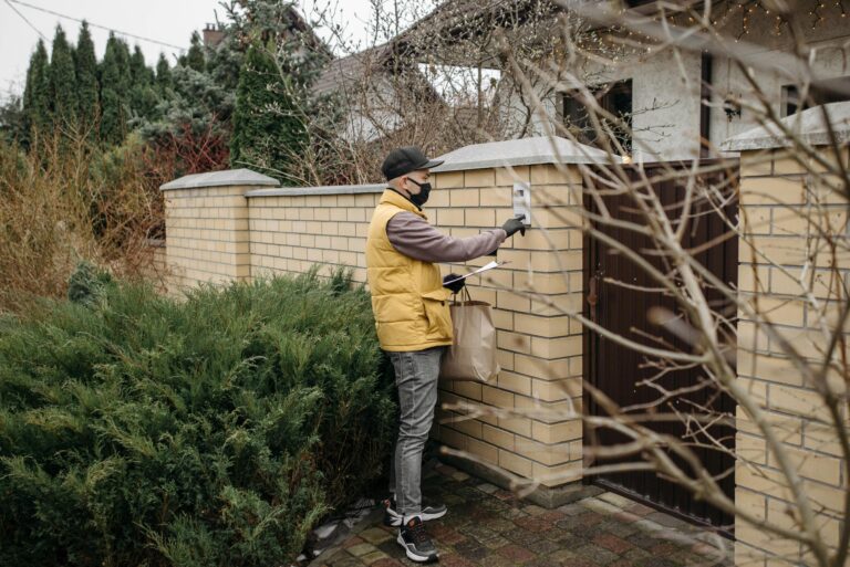 Courier presses doorbell delivering package amid pandemic precautions.